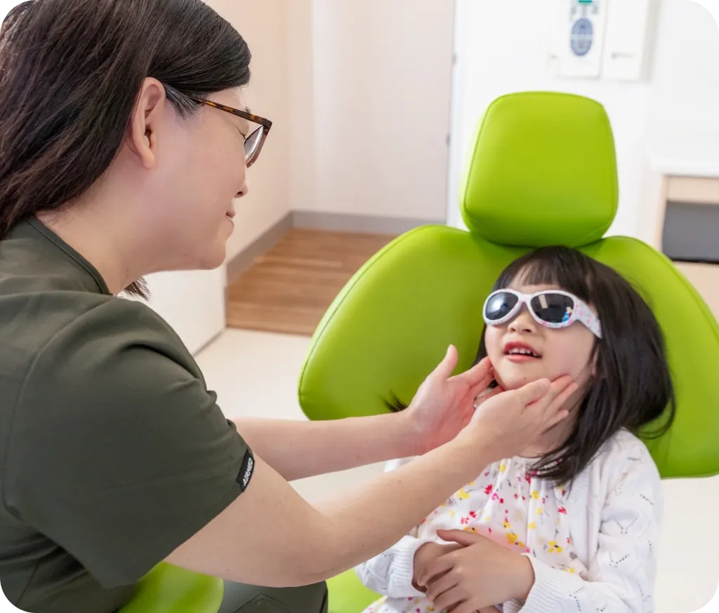 A gentle moment between Dr Leanne Tran and a young patient in the green CDG dental chair